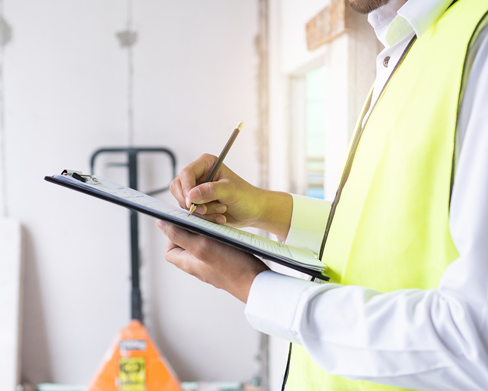 Construction professional in safety vest reviewing checklist on clipboard for workplace safety and OSHA compliance.